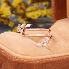 a close up of a pair of gold rings with diamonds on them and flowers in the background