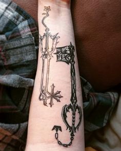 a person with a tattoo on their arm that has an image of two keys and a keyhole