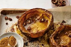 three baked desserts sitting on top of a baking sheet next to a bowl of nuts