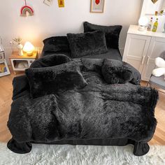 the bed is made up with black fluffy blankets and pillows on it, along with other decorations