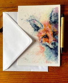 a card with a watercolor painting of a fox on it and a pen next to it