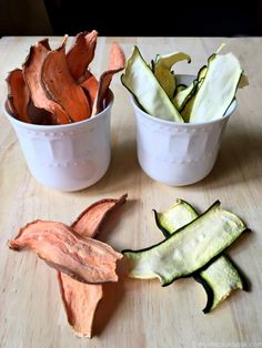 two white cups filled with sliced up vegetables