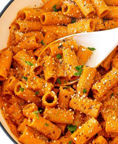 a bowl filled with pasta and topped with parmesan sprinkles next to a white spoon