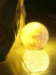 a large ball sitting on the ground next to a rock