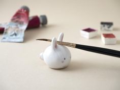 a pen sitting on top of a small white animal figurine next to other miniature items