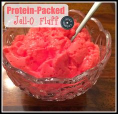 a glass bowl filled with red jello on top of a wooden table