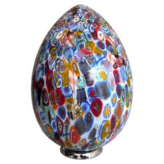 a colorful glass egg sitting on top of a metal stand