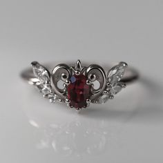 Inspired by Neo-Queen Serenity's crown from the Sailor Moon anime that I watched religiously as a child, this ring is both delicate and regal. The center garnet is set inside a golden heart with a tiny fleur-de-lis crown and diamond wings. CUSTOMIZE GEMSTONES ✶ solid 14 karat recycled yellow, white, or rose gold✶ band measures 1.6mm wide x 1.4mm thick✶ center stone: 0.33 carat, VS clarity, AA grade natural rhodolite garnet✶ accent stones are 0.22 total carat weight VS clarity lab-grown diamondsT