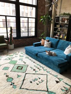 a blue couch sitting on top of a rug in a living room next to a window