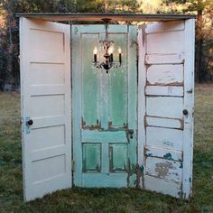 an open door with chandelier hanging from it's side in the grass