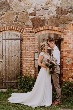 a bride and groom are standing in front of an old brick building with wooden doors