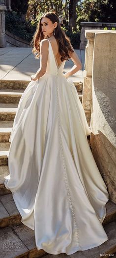 a woman in a white wedding dress standing on steps with her back to the camera