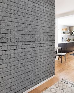 a living room with a brick wall and wooden flooring next to a dining area