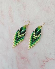 green and white beaded earrings on a marble surface