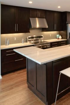 a large kitchen with an island in the middle and stainless steel appliances on both sides