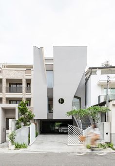 a person riding a bike in front of a white building with stairs and balconies