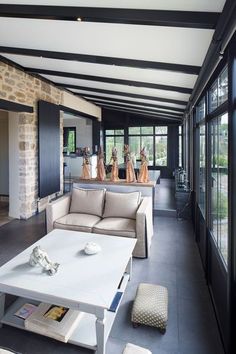 a living room filled with furniture next to large glass windows on top of a stone wall