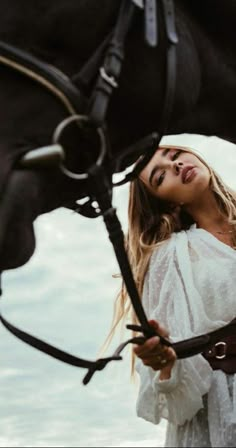 a beautiful woman standing next to a black horse