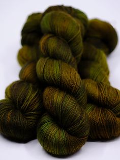 several skeins of green and brown yarn on a white table top with one skein in the foreground