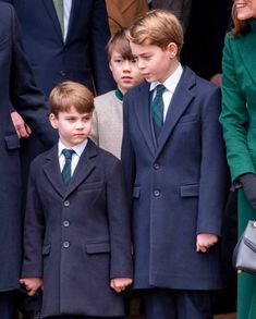 two young boys in suits and ties standing next to each other with people behind them