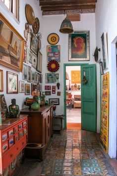 a hallway with many pictures on the wall and an open door leading to another room