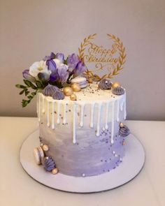 a white cake with purple icing and seashells on the top is sitting on a table