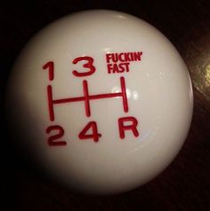 a white frisbee with red writing on it sitting on a wooden table next to a light