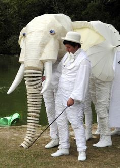 an elephant mask is being held by two men in white suits and hats, with one man holding a golf club