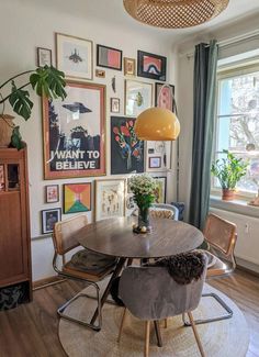 a dining room table and chairs in front of a window with pictures on the wall