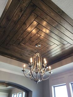 a chandelier hanging from the ceiling in a room with wood paneling on it