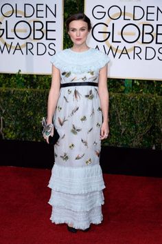 a woman in a white dress standing on a red carpet