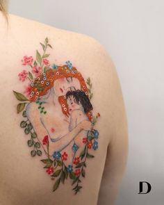 the back of a woman's shoulder with flowers and leaves around her shoulders, which has an image of two people embracing each other