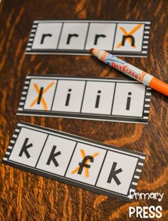 two pieces of paper with the letters k and k on them next to an orange crayon marker