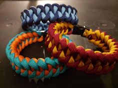 three different colored bracelets sitting on top of a black table next to each other