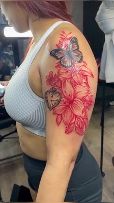 a woman with a butterfly and flower tattoo on her arm, sitting in front of a mirror