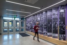 a man is walking in front of a wall with pictures on it