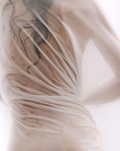 the back of a woman's body with white sheer fabric covering it and her hands on her hips