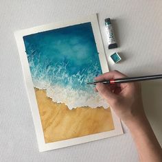 a person is painting an ocean scene with watercolors