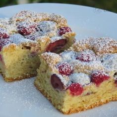 two pieces of cake on a plate with powdered sugar and raspberry topping