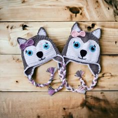 two crocheted hats with blue eyes and a pink bow