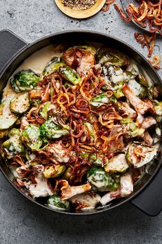 a skillet filled with cooked vegetables on top of a table next to some onion rings