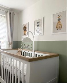 a baby crib with pictures on the wall above it and a stuffed giraffe