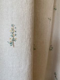 closeup of curtains with embroidered flowers and leaves on them, in white linen fabric