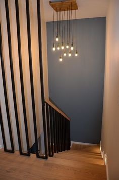 the light fixture is hanging from the ceiling above the stairs in this hallway with striped walls and wood flooring