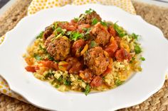 a white plate topped with meatballs and rice on top of a woven place mat