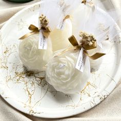 three white roses wrapped in organe ribbons on a plate with gold flecks