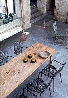 a wooden table sitting on top of a cement floor next to chairs and a bench