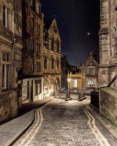 an old cobblestone street at night with the moon in the sky