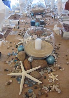 the table is set with starfish, rocks and candles for an ocean themed dinner