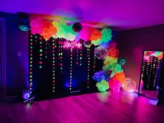 a party room with balloons and streamers on the wall, neon lights in the background